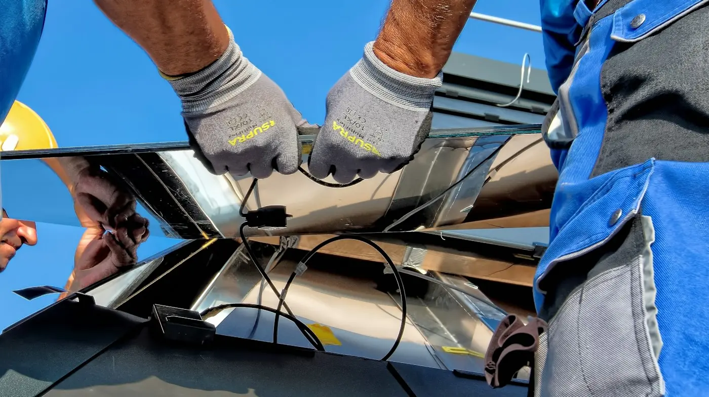 Manos con guantes ajustando la estructura de un módulo solar